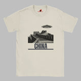 Sand coloured T-shirt with a vintage black-and-white Great Wall of China illustration and a UFO hovering above it, labeled ‘CHINA,’ designed by MytsDesigns.com”

