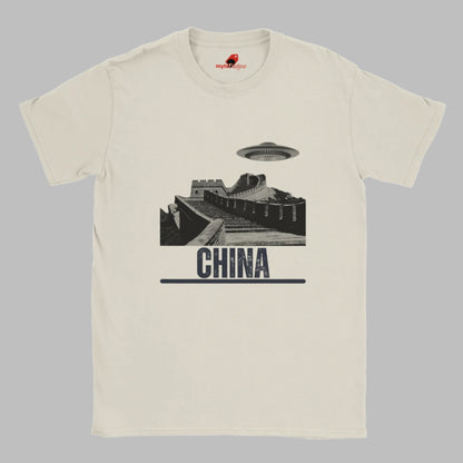 Sand coloured T-shirt with a vintage black-and-white Great Wall of China illustration and a UFO hovering above it, labeled ‘CHINA,’ designed by MytsDesigns.com”

