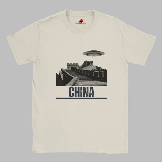 Sand coloured T-shirt with a vintage black-and-white Great Wall of China illustration and a UFO hovering above it, labeled ‘CHINA,’ designed by MytsDesigns.com”

