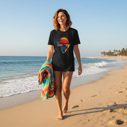 Woman walking on a beach with a colorful towel, wearing a black t-shirt with a graphic design.