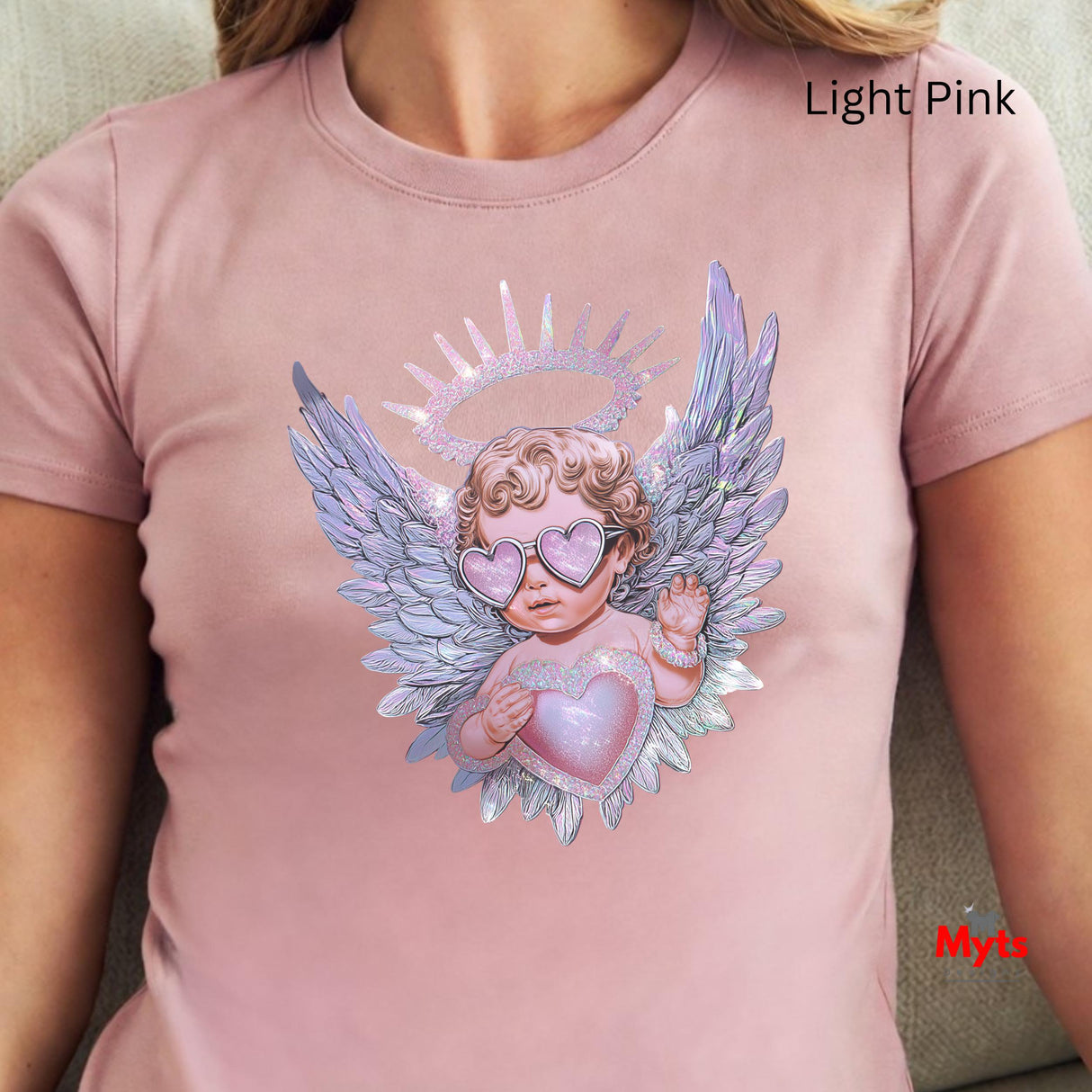Light pink t-shirt with an angel design featuring wings and a heart, worn by a person.