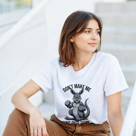 Woman wearing a white t-shirt with a kangaroo graphic and text, sitting on steps.