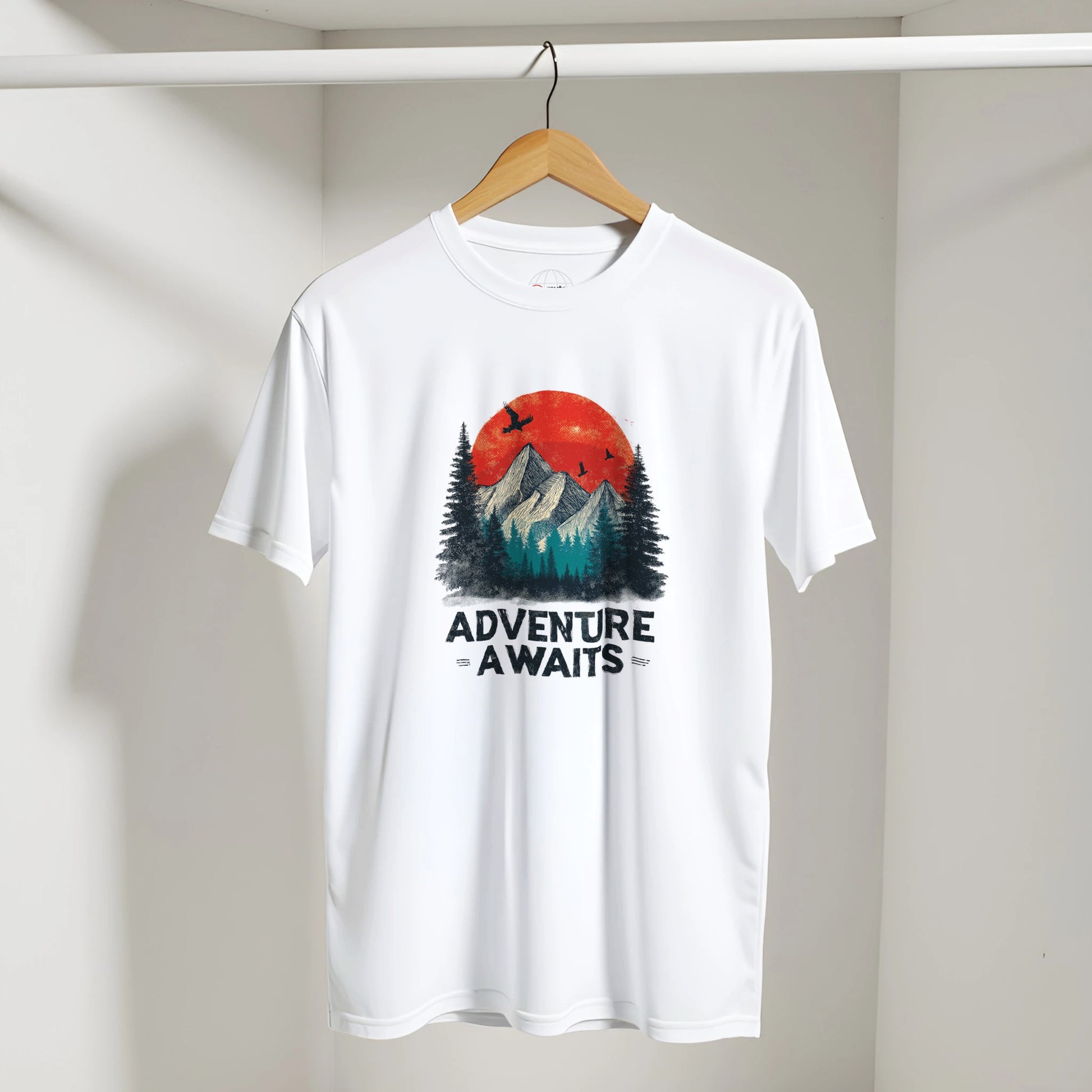 White t-shirt with 'Adventure Awaits' graphic on a hanger against a plain background
