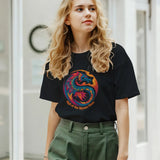 Front view of a woman wearing a black T‑shirt featuring a bold dragon symbol graphic centered on a soft cotton tee