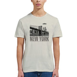 Sand colored soft casual tee showing the New York City skyline with a stylized spaceship graphic soaring above, worn by a young woman