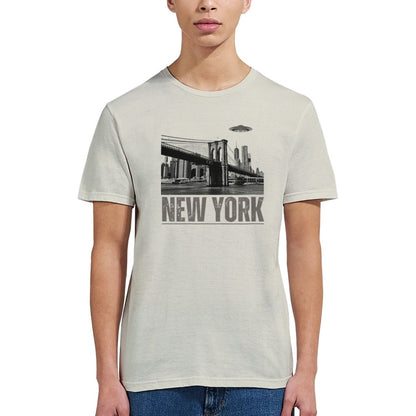 Sand colored soft casual tee showing the New York City skyline with a stylized spaceship graphic soaring above, worn by a young woman