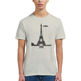 Front view of a sand soft casual sand tee featuring a whimsical graphic of the Eiffel Tower with a retro‑style spaceship orbiting it, worn by a young woman.