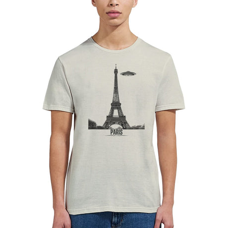 Front view of a sand soft casual sand tee featuring a whimsical graphic of the Eiffel Tower with a retro‑style spaceship orbiting it, worn by a young woman.