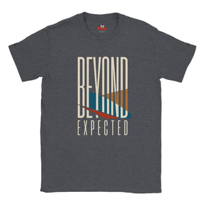 A dark heather gray t-shirt with a graphic print on the front that reads 'BEYOND EXPECTED' in cream lettering, featuring a stylized sunset design with blue, orange, and red geometric shapes.