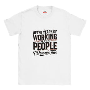 A white short-sleeve crewneck t-shirt with a graphic text print on the front that reads 'AFTER YEARS OF WORKING WITH PEOPLE I DESERVE THIS' in black and dark red lettering, displayed on a clean white background.