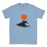 Light blue t-shirt with a graphic design of a person on a surfboard under an orange sun, on a white background.