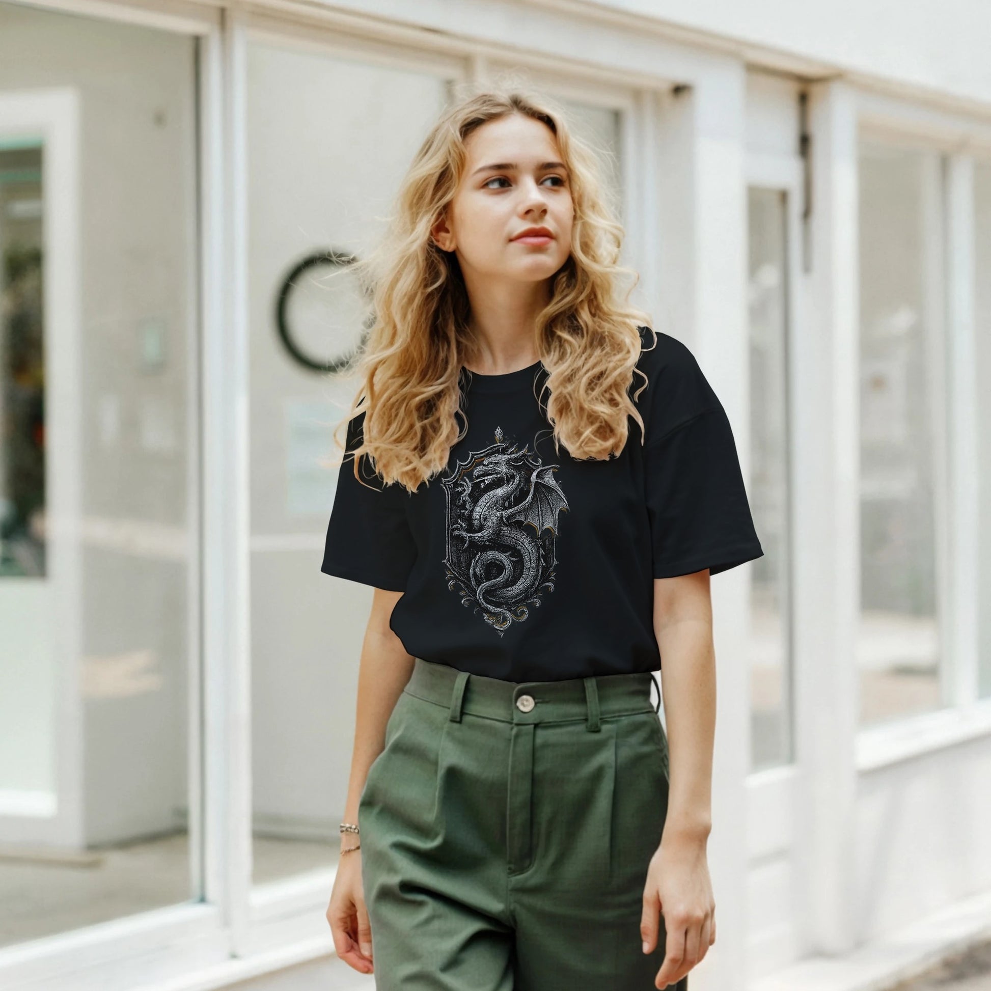 Woman wearing a black t-shirt with a dragon design and green pants outdoors.