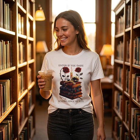 Woman in a library wearing a t-shirt with a bookshelf design, holding a drink.