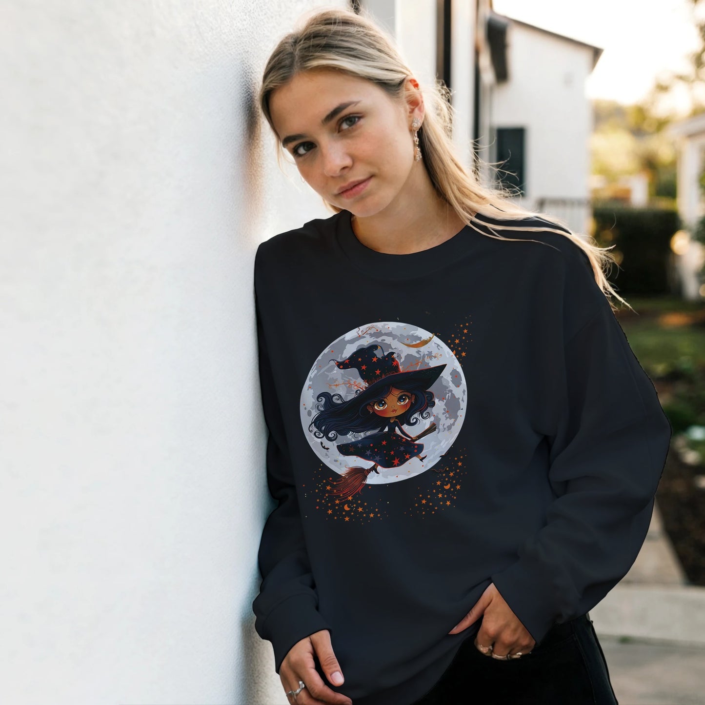 Woman wearing a black sweatshirt with a witch graphic design outdoors.