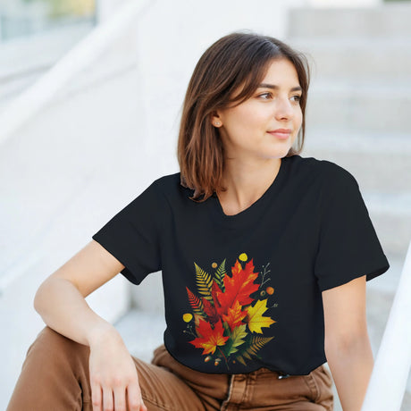 Woman wearing a black t-shirt with a colorful leaf design, sitting on steps.