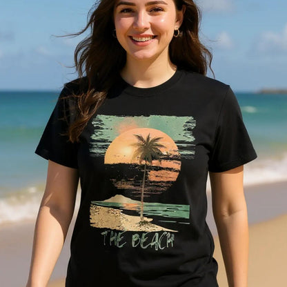 Front view of vintage beach T-shirt featuring palm trees and retro sunset graphic on black cotton tee worn by a woman waking on a beach