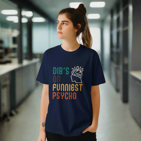 Front view of a young woman wearing a casual tee featuring retro script that reads “Dibs on Funniest Psycho” in distressed vintage style, printed on ultra-soft navy Gildan 64000 cotton