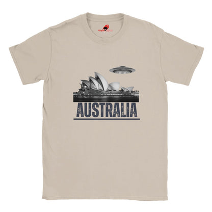Front view of a sand colored soft casual tee showing the Sydney Opera House sails with a sleek spaceship graphic orbiting overhead, printed on ultra-soft Gildan 64000 cotton.