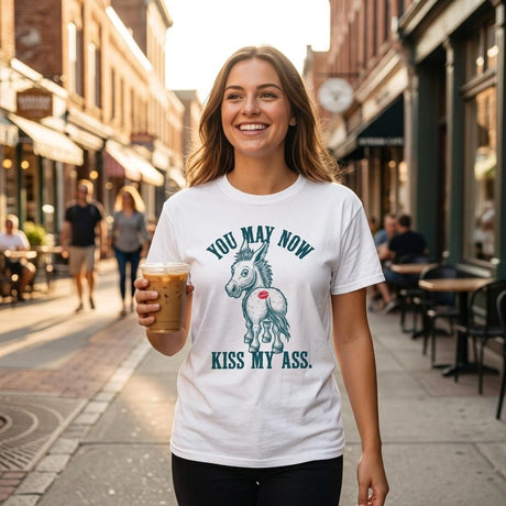 Woman wearing a white t-shirt with a graphic design and text, holding a drink on a street.