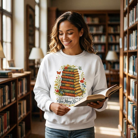 Woman in a library wearing a sweatshirt with a book design, holding an open book.