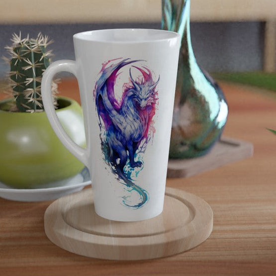 A tall white ceramic mug with a colorful abstract blue, purple, and pink dragon illustration, displayed on a round wooden coaster on a wooden table.