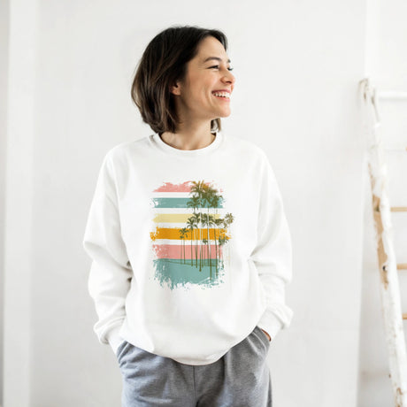 Woman wearing a white sweatshirt with a colorful palm tree design against a white background