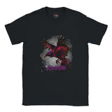 Black unisex T-shirt with a vivid magenta-and-black raven in flight against a smoky grey background and gothic purple “RAVEN” text, modeled outdoors by MytsDesigns.
