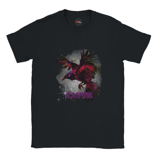 Black unisex T-shirt with a vivid magenta-and-black raven in flight against a smoky grey background and gothic purple “RAVEN” text, modeled outdoors by MytsDesigns.