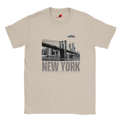 Sand colored soft casual tee showing the New York City skyline with a stylized spaceship graphic soaring above, printed on ultra-soft Gildan 64000 cotton.