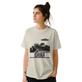 “Woman wearing a white T-shirt with a vintage black-and-white Great Wall of China illustration and a UFO hovering above it, labeled ‘CHINA,’ designed by MytsDesigns.com in a gym setting”

