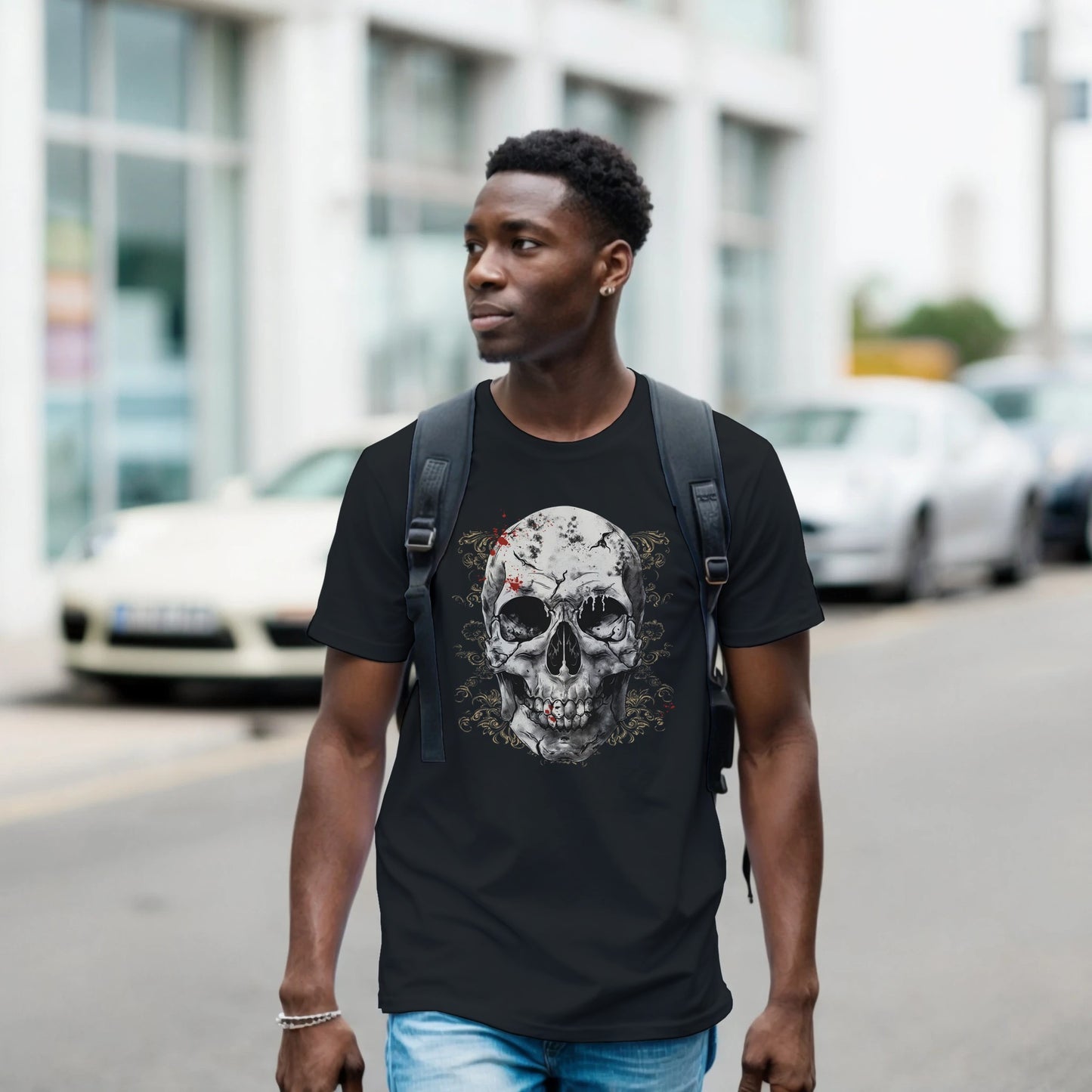 Man wearing a black t-shirt with a skull design on a street.