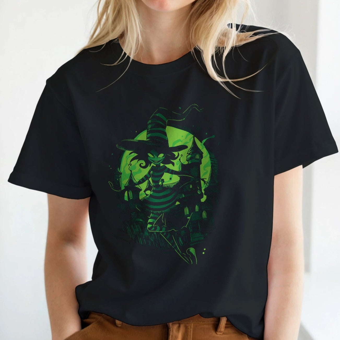 Person wearing a black t-shirt with a green graphic design in a bright room.