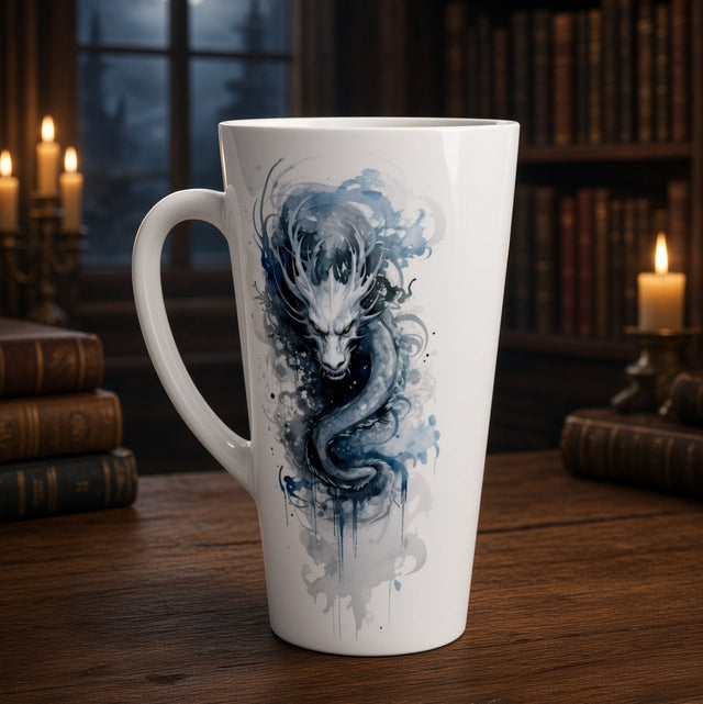 A tall white ceramic mug with a blue and gray watercolor dragon design, set on a wooden table in a dimly lit library with candles and bookshelves in the background.