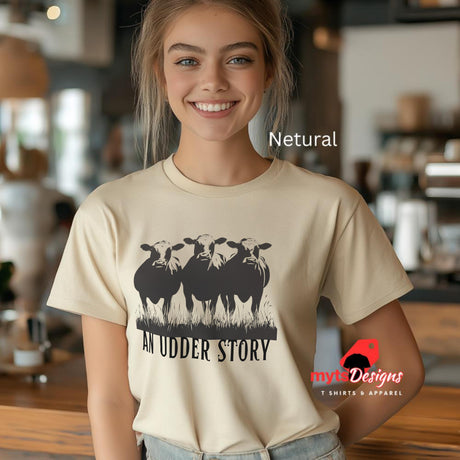 Young woman wearing a neutral cotton T-shirt featuring illustrated cows and text “An Udder Story” – humorous farm-themed graphic tee