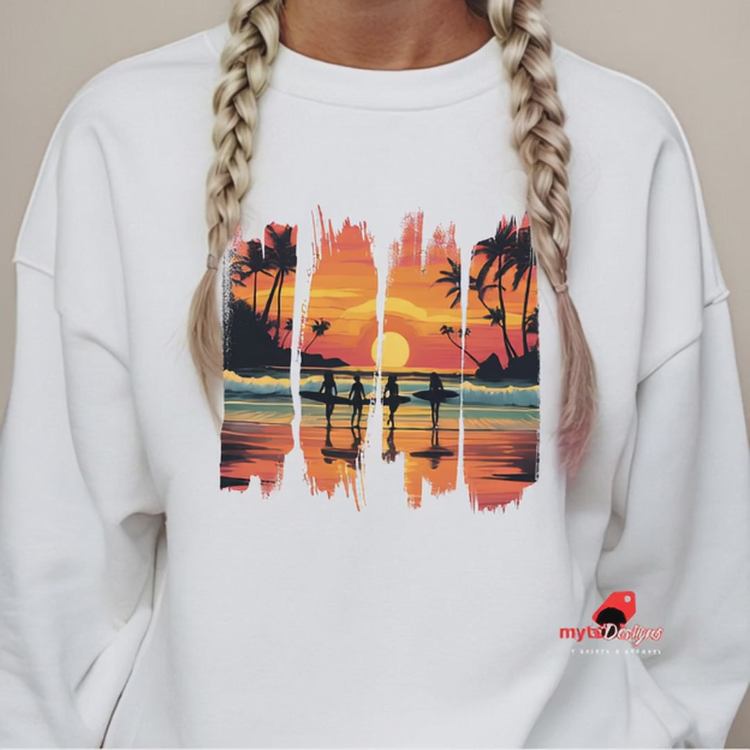 A white unisex sweatshirt featuring a vibrant tropical sunset design with silhouettes of surfers walking along a beach. The graphic includes palm trees, an orange and pink sky, and artistic brushstroke edges, creating a modern coastal vibe. Ideal for beach lovers, surfers, and casual fashion fans.

