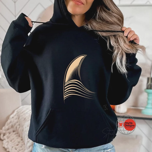 Black minimalist surf hoodie featuring elegant golden wave graphic worn in a cozy modern coastal lifestyle setting